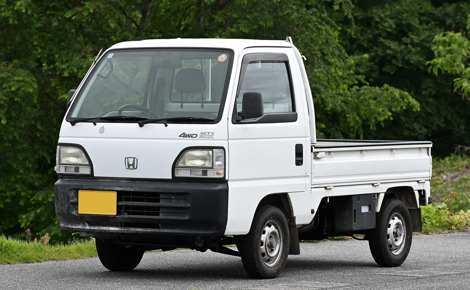 White Honda Acty SDX 4WD kei truck from the late 1990s, parked by trees