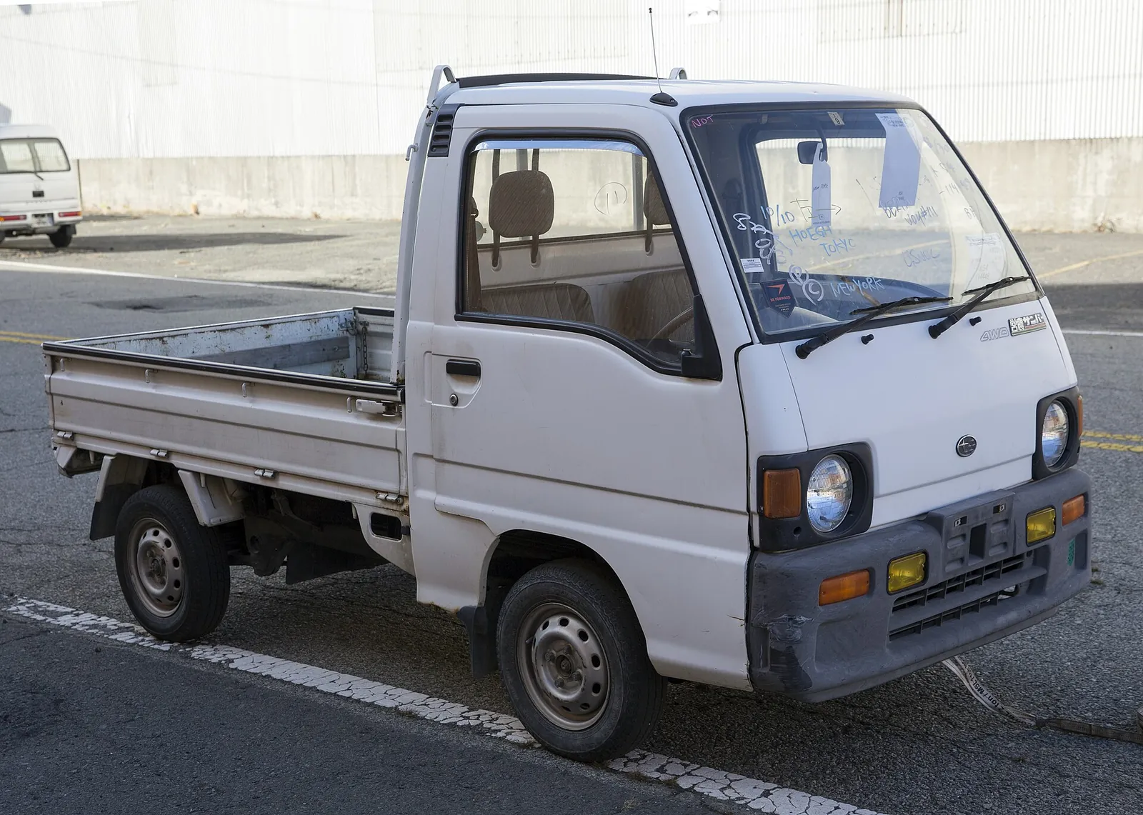 White 1992 Subaru Sambar 4WD kei truck with a flat bed, parked on a street