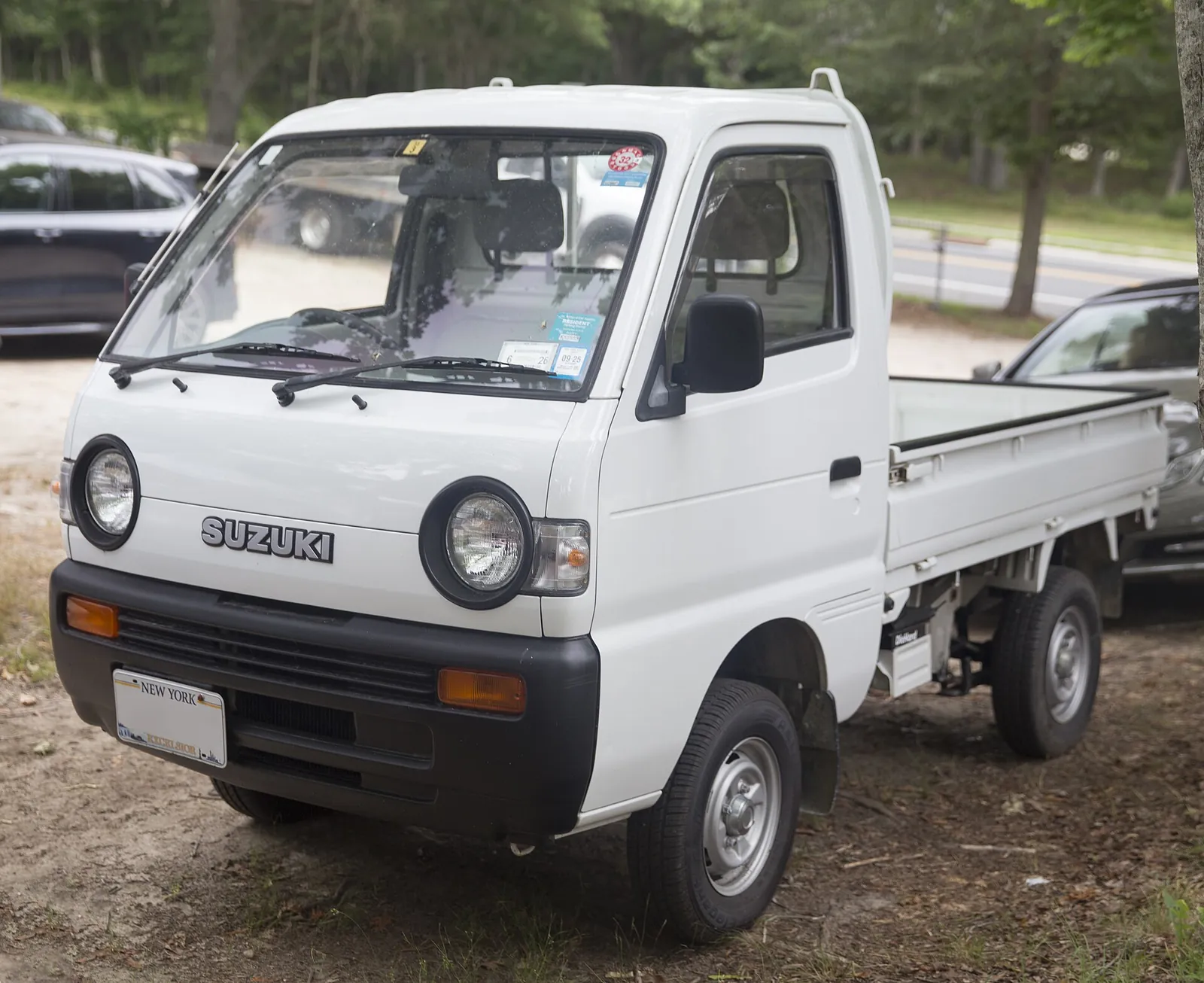 White 1994 Suzuki Carry 4WD kei truck with round headlights, parked on dirt