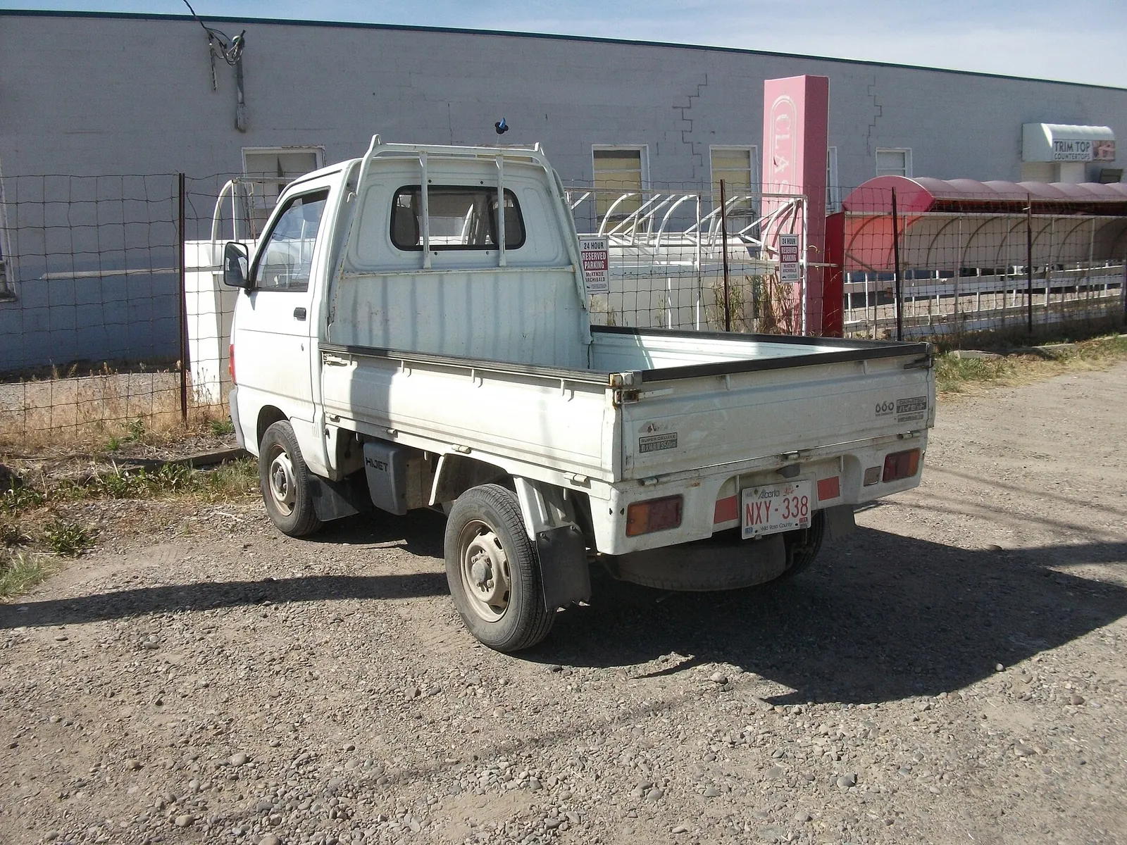 White Daihatsu Hijet kei truck imported from Japan, parked on a gravel lot in Canada